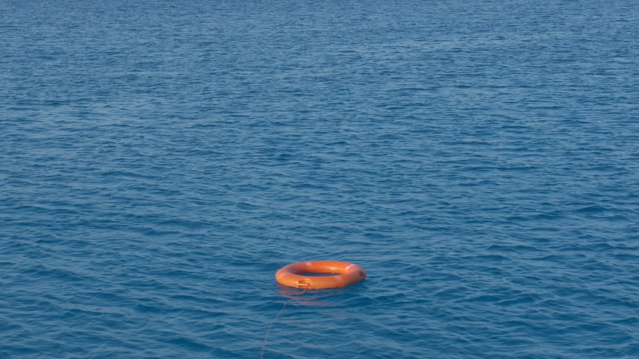 하나의 빨간색 구명 구명 조끼가 열린 물에 떠 있습니다.