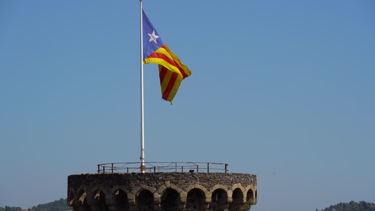 Bandiera catalana che sventola alta su una torre in un castello medievale