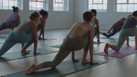 Clase-De-Yoga-De-Mujeres-Sanas-Practicando-Pose-De-Estocada-Creciente-En-El-Gimnasio-Al-Amanecer-Disfrutando-Del-Ejercicio-Temprano-En-La-Mañana