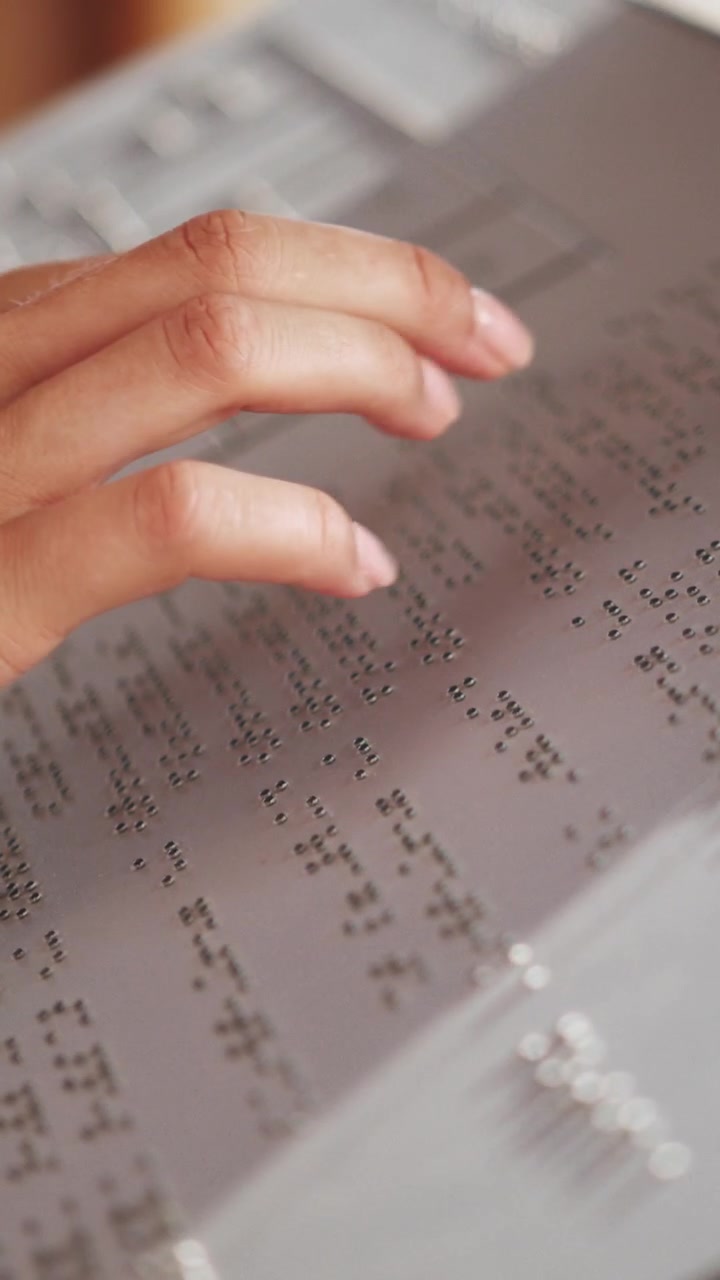 A closeup shot of a hand reading braille on a page the focus is on the fingertips gently touching