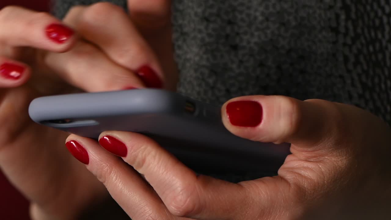 woman hands with red manicure holding mobile phone and texting