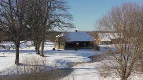 Historic old wooden family house surrounded by large trees in countryside on a sunny day in winter scenery. Lifestyle of living in countryside.