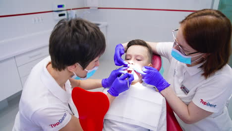 Dentist checks the child teeth. Child patient sitting on dental chair in paediatric dentists office