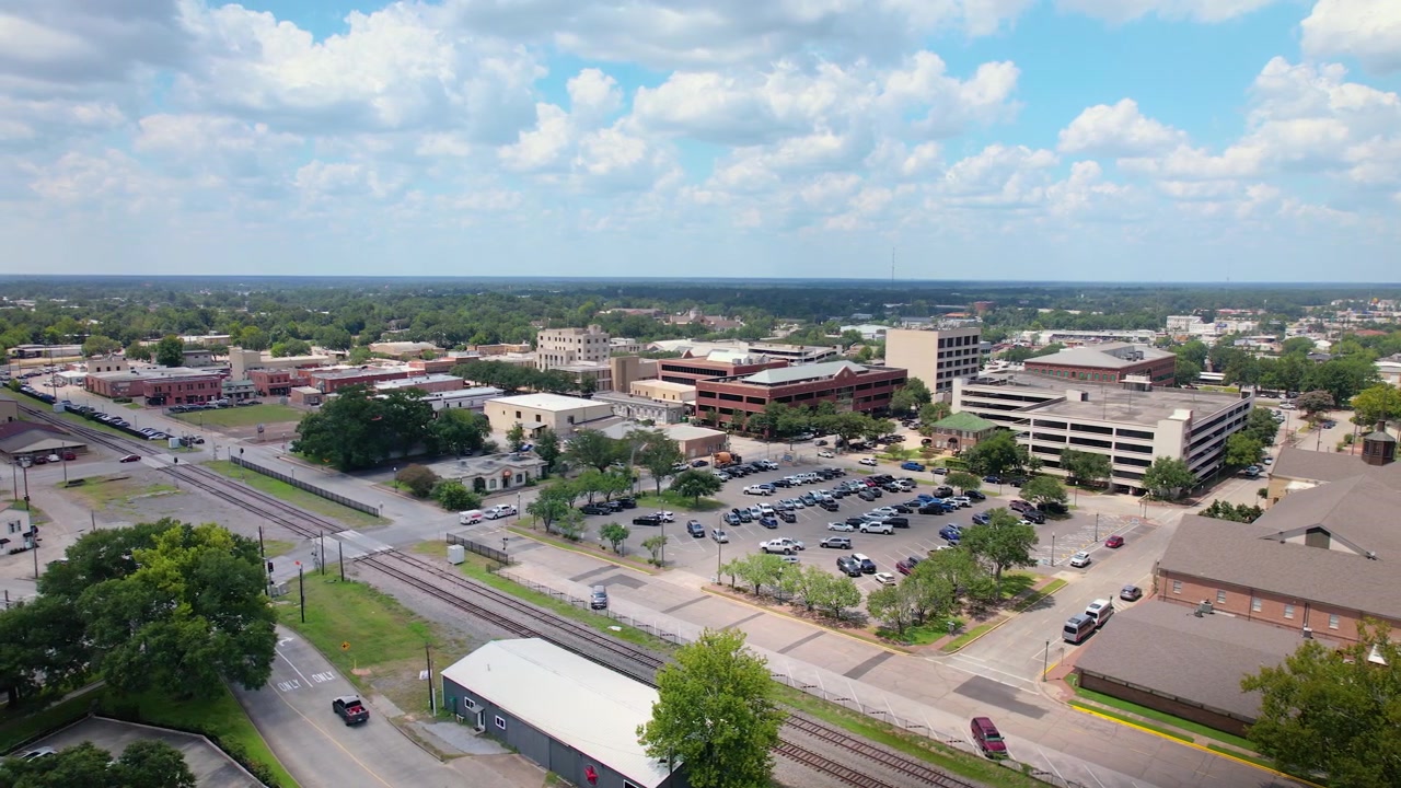 Riprese aeree con drone che si muovono lateralmente attraverso Downtown Conroe, Texas, creando una vista in parallasse del tribunale della contea di Montgomery e degli edifici circostanti del centro, strade, aree di parcheggio e ferrovia