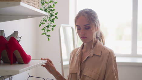 woman takes delicate white blouse on hanger in fitting room