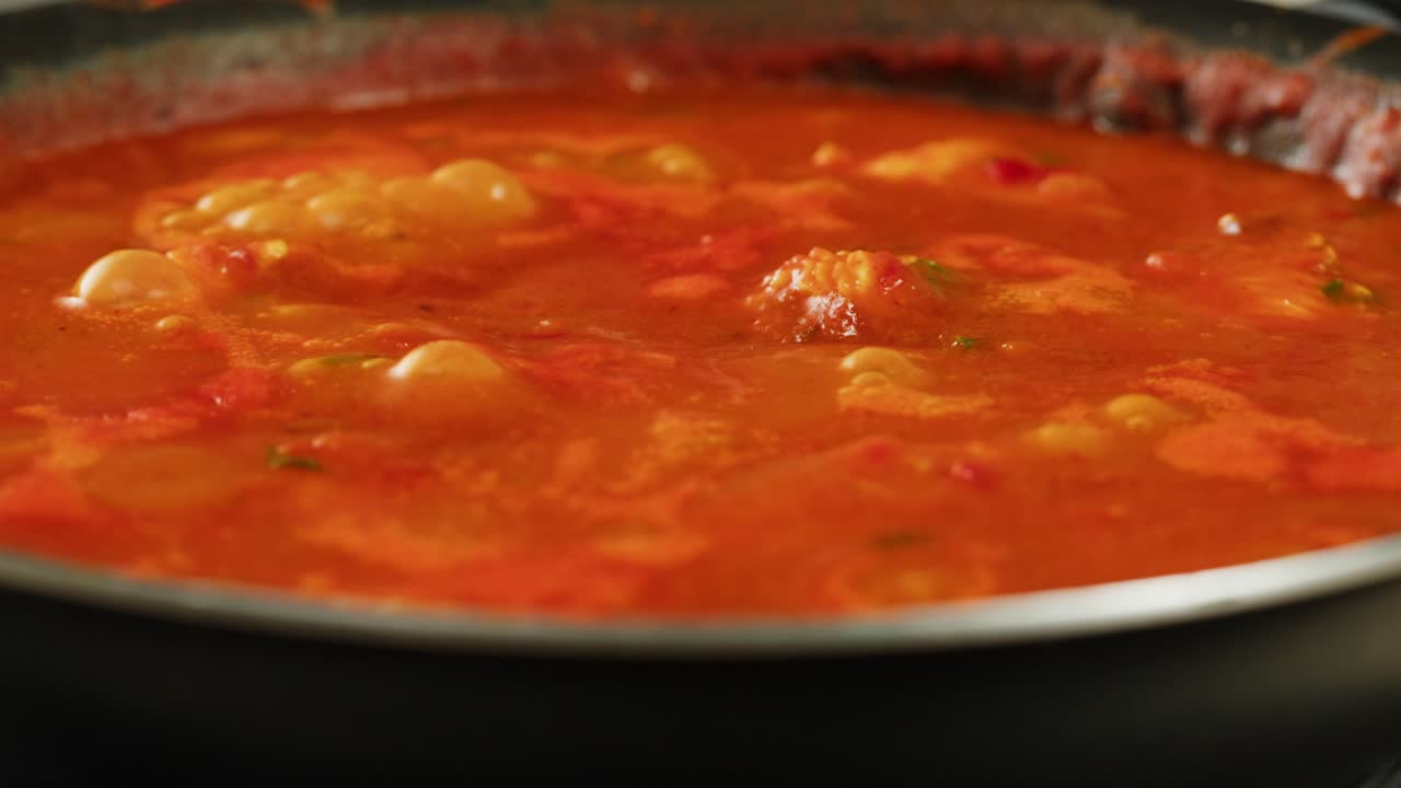 Boiling tomato sauce on a frying pan close-up. Cooking tomato sauce or soup. Traditional Italian Mexican Asian dish. High quality studio shot for cafe, restaurant close up. Marinara sauce for Italian pasta