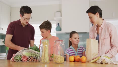 happy caucasian family unpacking bags with vegetables