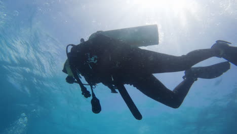 Cinematic-underwater-shot-of-a-scuba-diver-against-the-sunlight-in-slow-motion,-4K,-120FPS,-Slomo