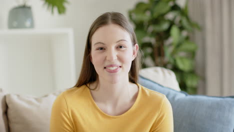 Portrait-of-happy-caucasian-woman-sitting-on-sofa-and-smiling-at-home,-in-slow-motion