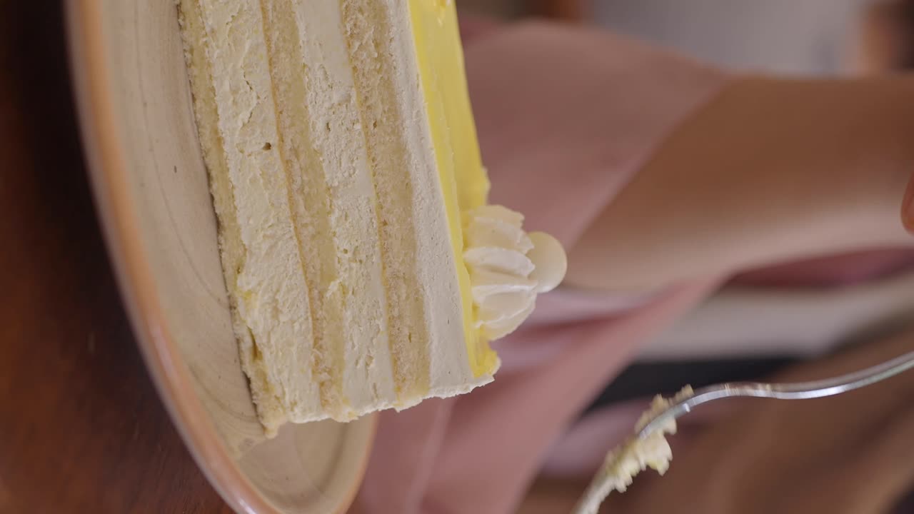 A close-up of a person eating a slice of layered cake with a fork