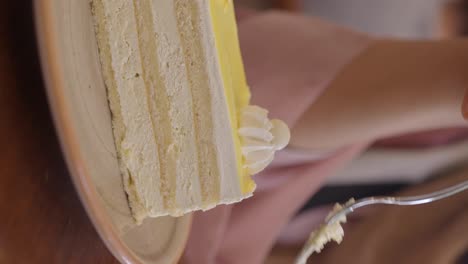 a close-up of a person eating a slice of layered cake with a fork