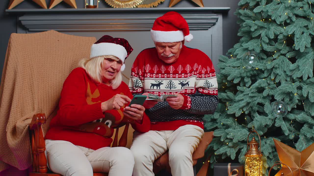 pareja de familiares mayores buscando comprar regalos de navidad en línea en aplicaciones de teléfonos móviles en casa