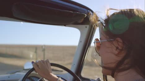 beautiful girl driving vintage car on road trip