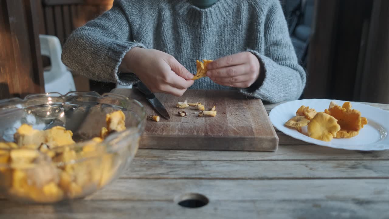 hembra limpiando hongos chanterelle dorados en una mesa de madera, vista frontal
