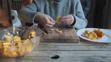 Weibchen-Putzt-Goldene-Pfifferlinge-Auf-Holztisch,-Vorderansicht