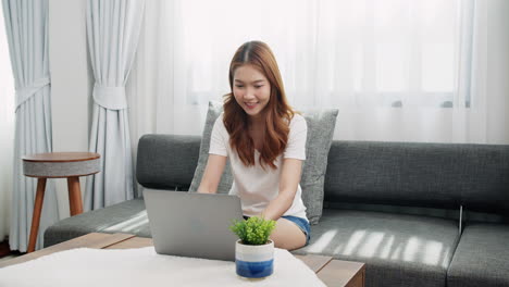 Smiling-young-businesswoman-using-laptop-sitting-at-home-office-desk,-happy-female-customer-make-distant-online-work