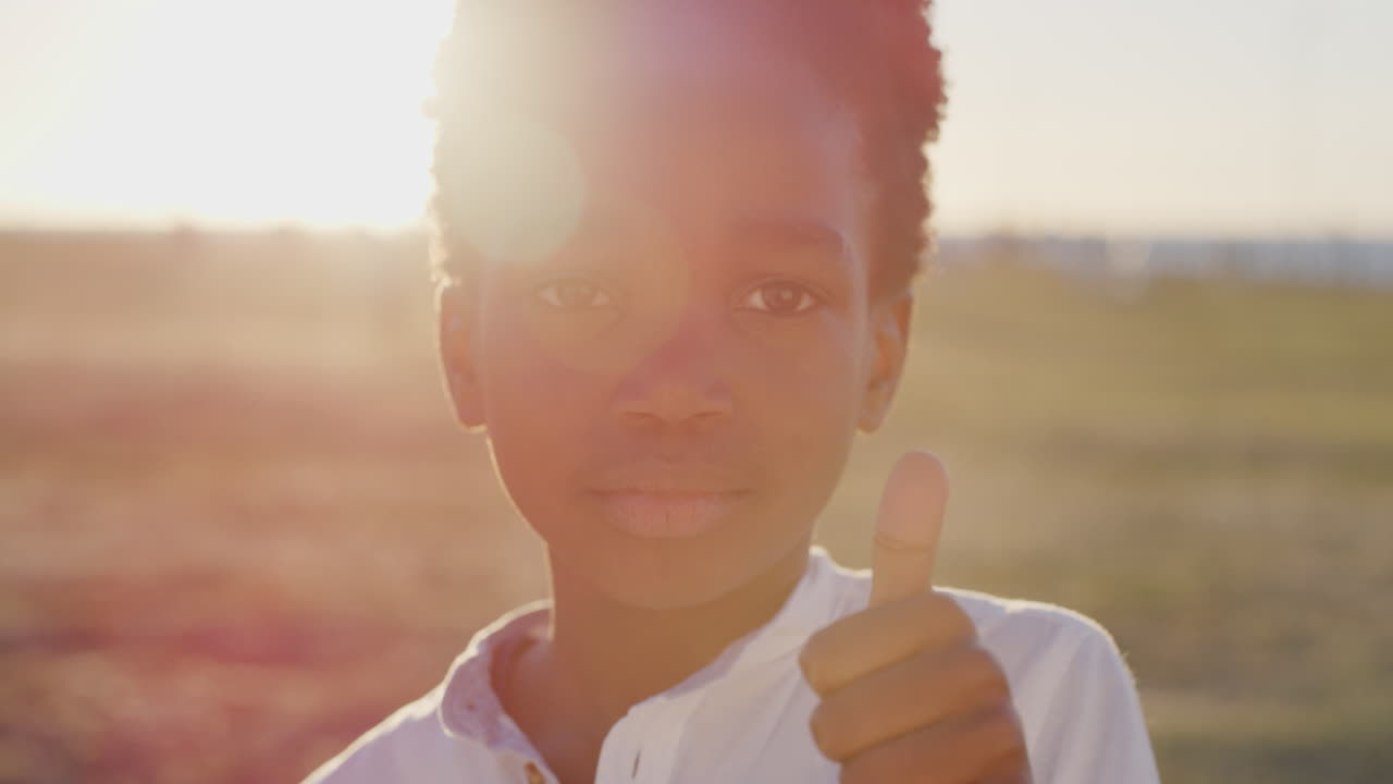 close up portrait little african american boy thumbs up smiling happy enjoying seaside park sunset background hopeful positive youth