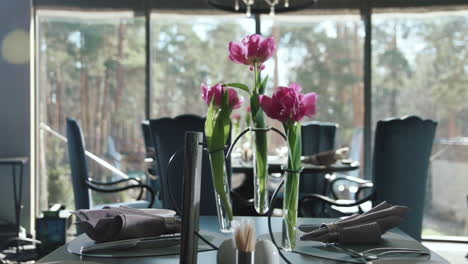 plate with napkin and cutlery for dinner in restaurant. flowers on dining table