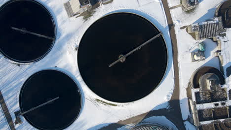 top down aerial of basin at sewage water treatment plant in winter - drone setting down