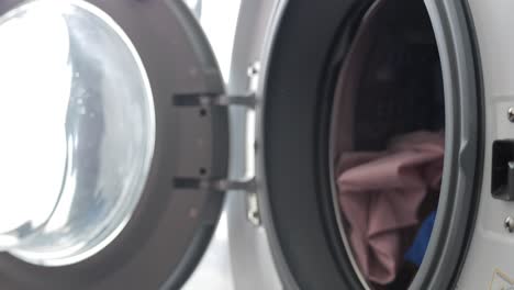 Filling-Washing-Machine-With-Multi-Colored-Dirty-Clothes-And-Garments-Close-Up