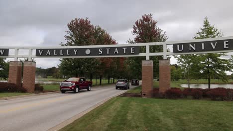 entrance with cars driving on the campus of saginaw valley state university in university center, michigan in slow motion