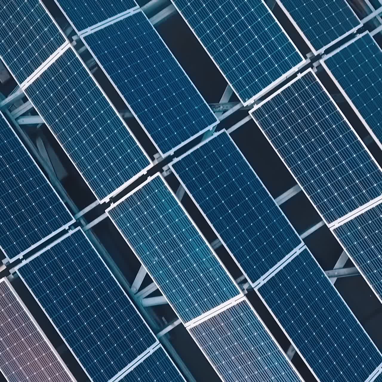 Top view of innovative solar panel collections on roof. Blue photovoltaic panels to get clean ecological energy from the sun. Motion camera back. Drone view.