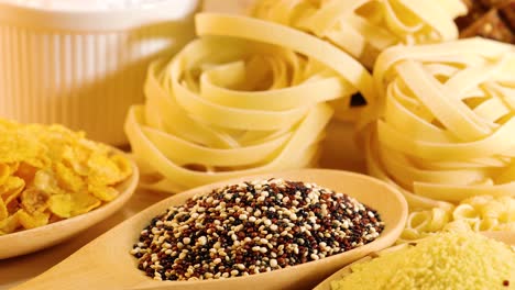 a close-up view of various grains and pasta arranged under warm lighting, highlighting textures and colors