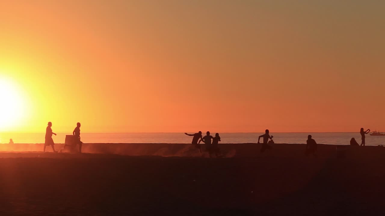 알아볼 수 있는 사람도 없고, 해변에서 여름의 즐거운 시간을 보내고, 눈부신 일몰을 배경으로 축구 경기를 즐기는 젊은 사람들