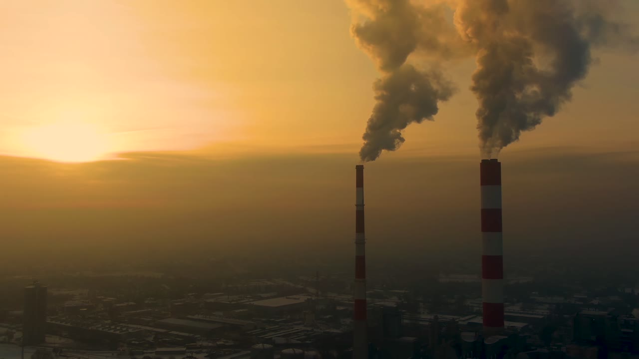 Power Plant emissions seen above the city during sunrise. Environmental pollution. Factory pipe polluting air.Panorama sunset. Smoking pipes Aerial view,