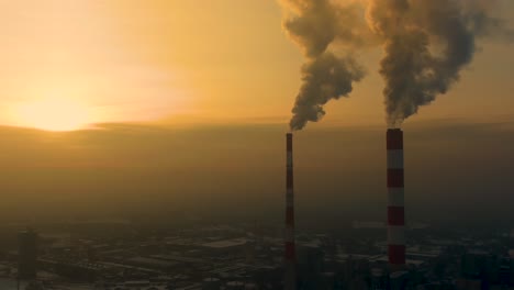 Power Plant emissions seen above the city during sunrise. Environmental pollution. Factory pipe polluting air.Panorama sunset. Smoking pipes Aerial view,