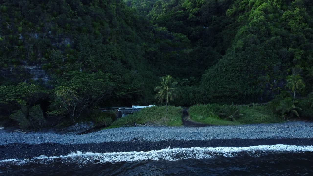 A dolly zoom in from an aerial drone that captures the beauty of East Maui's rocky shore, where jagged cliffs meet the crashing waves of the Pacific, showcasing the wild, untamed coastline of Hawaii