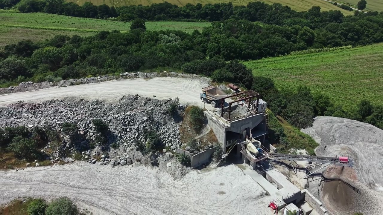 Granite quarry located near a green landscape shows machines working and material extraction in progress in the daytime