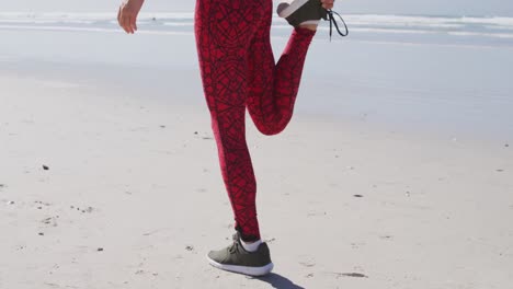 mujer caucásica estirándose y corriendo en la playa y el fondo del cielo azul