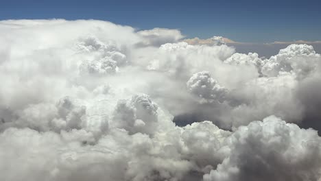 a pilot’s perspective taken from inside the cockpit of a jet airplane flying at very high altitude at cruise over threatening storm clouds under a blue sky. ultra-realistic aerial shot.