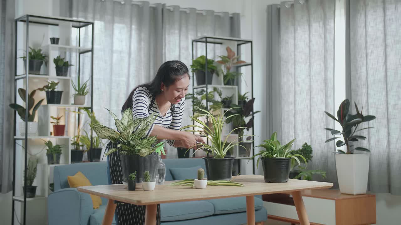 Wanita Asia Tersenyum Memegang Gunting Pangkas dan Memangkas Tanaman di Rumah