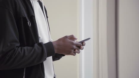 Hands-of-young-African-American-man-using-smartphone