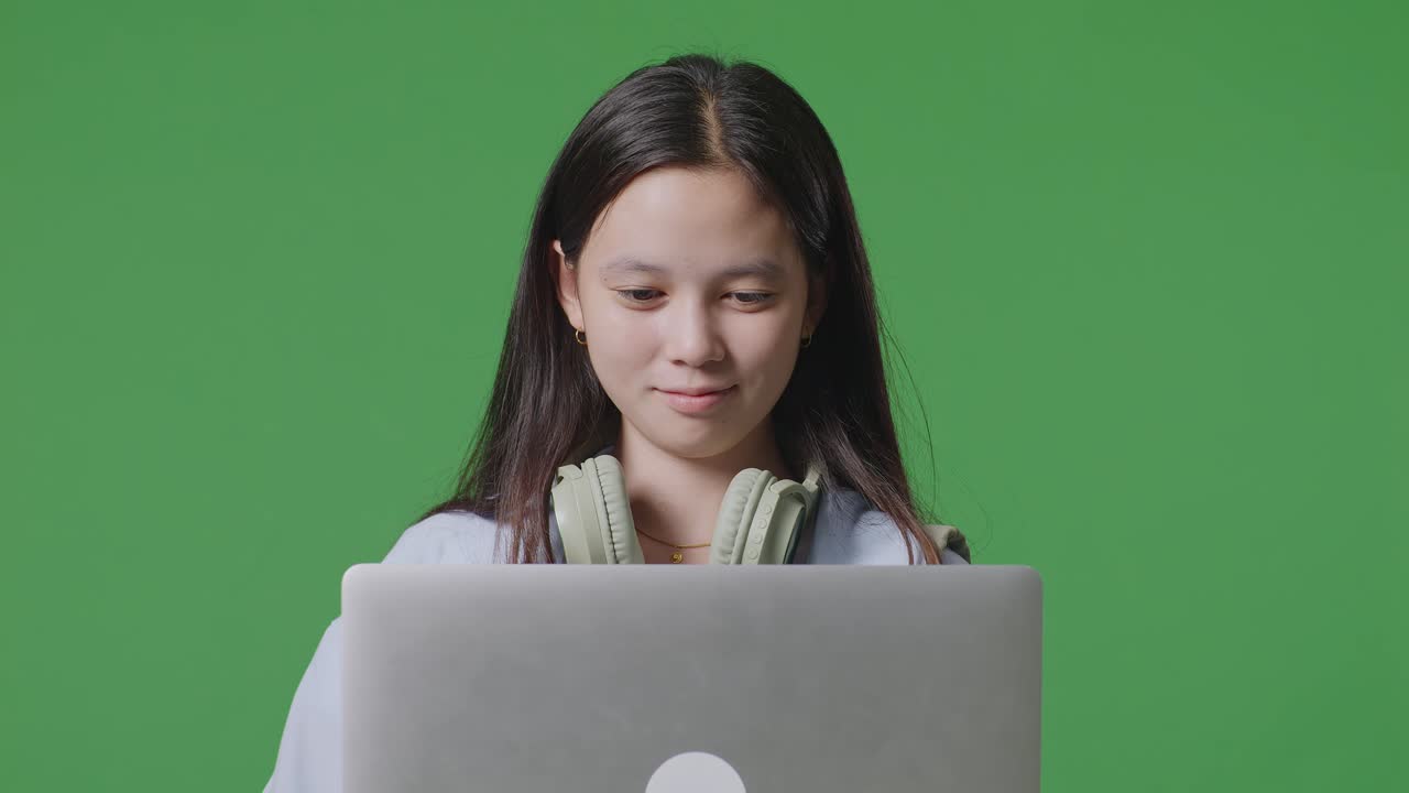 녹색 스크린 배경 스튜디오에 서서 에서 미소 짓고 타이핑하는 배을 가진 아시아 십대 소녀 학생의 클로즈업