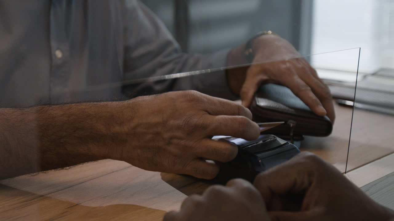 Person using credit card at a payment terminal with a protective screen