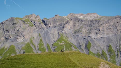 excursionistas en órbita parados en una colina junto a la cruz con altas montañas en el fondo croix de javerne - los alpes, suiza