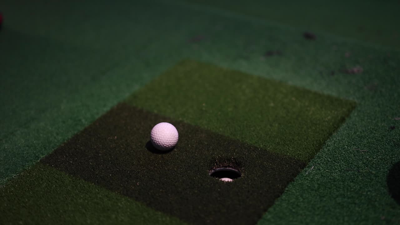 Golf ball rolling towards hole on putting green.