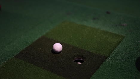 golf ball rolling towards hole on putting green.