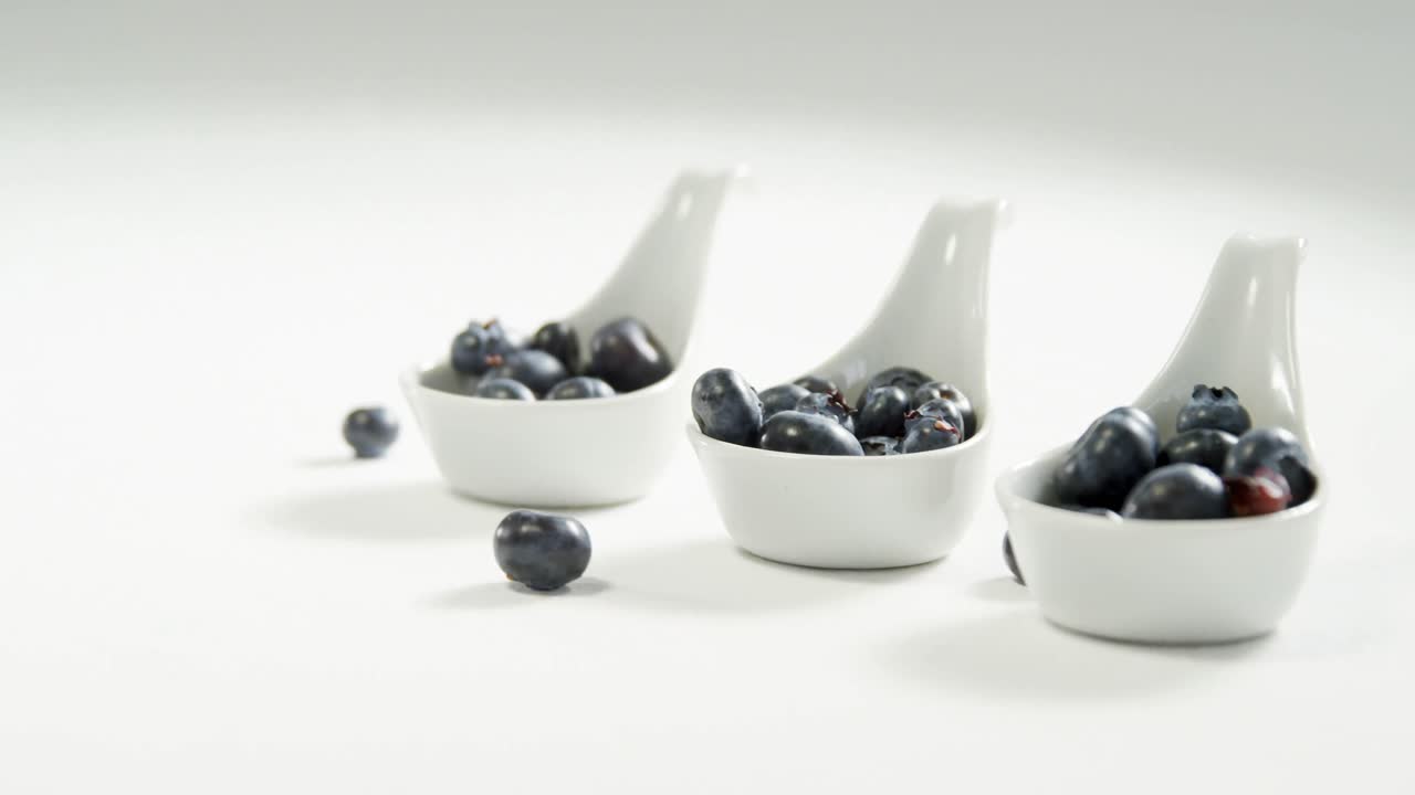 Blueberries in soup spoon placed on white surface 4K 4k