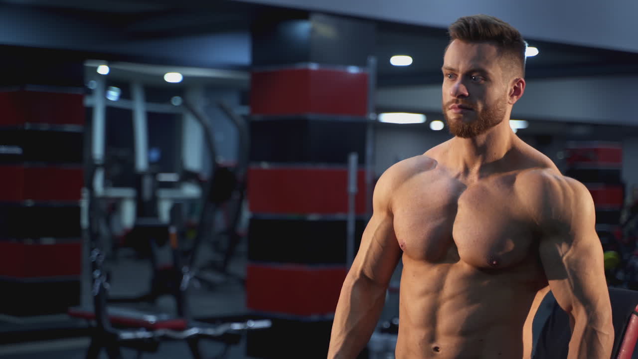 Handsome bodybuilding man have a rest after training. Young shirtless man training hard on the gym.