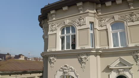 a man in a suit looks out of a window in a city