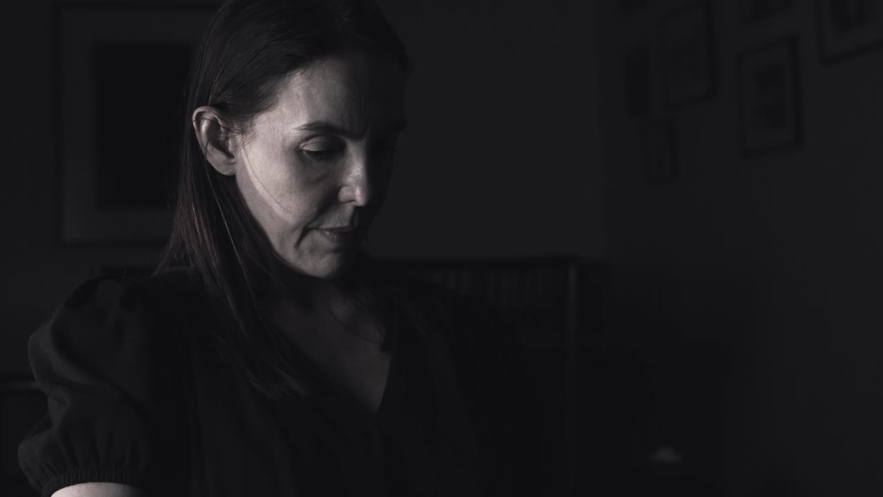 mujer en una habitación oscura reflexionando en un pensamiento profundo mientras mira un libro de imágenes