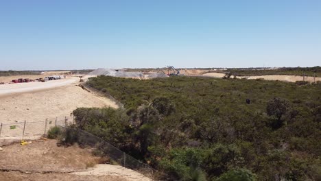 Dolly-Tiro-A-La-Derecha-Sobre-Matorrales-Cerca-Del-Sitio-De-Las-Obras-De-Construcción-De-La-Nueva-Estación-De-Alkimos