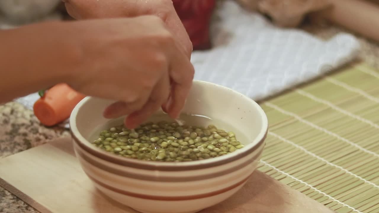 Washing mung beans in a bowl of water, preparing it for cooking