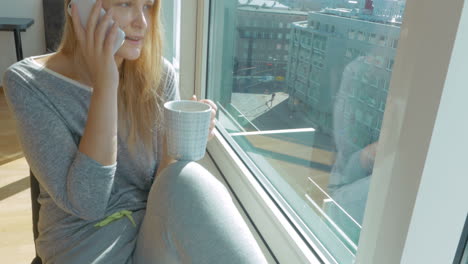 Woman-having-phone-talk-and-drinking-tea