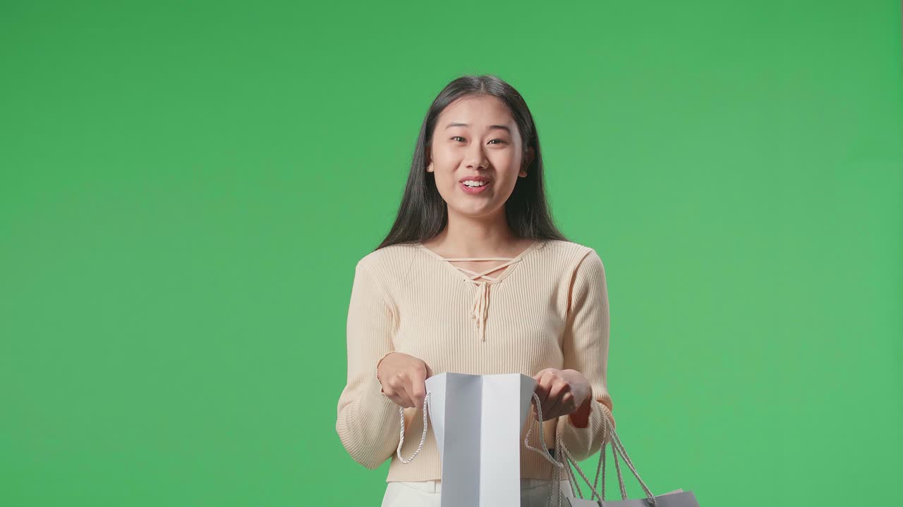 An Asian Shopping Woman Being Happy After Opening Shopping Bag While Standing In Front Of Green Screen