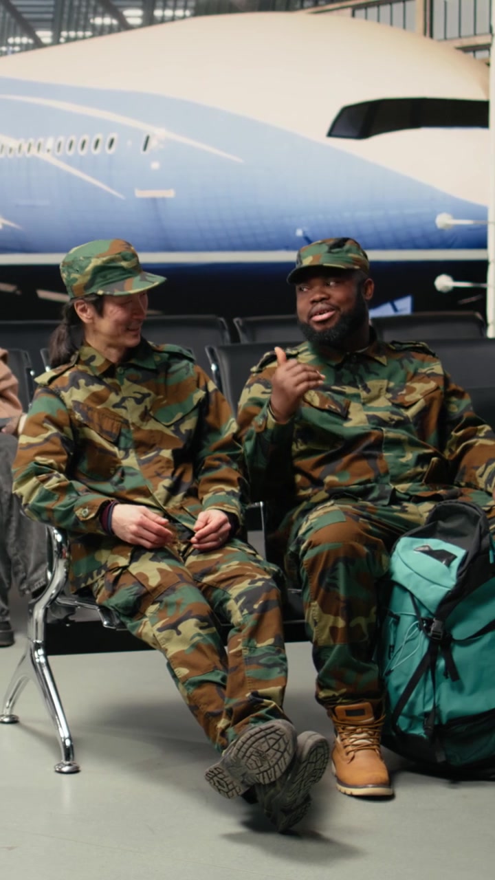 Video verticale: Chiacchiere, volo di viaggio e soldati dell'esercito seduti su sedie in aeroporto.